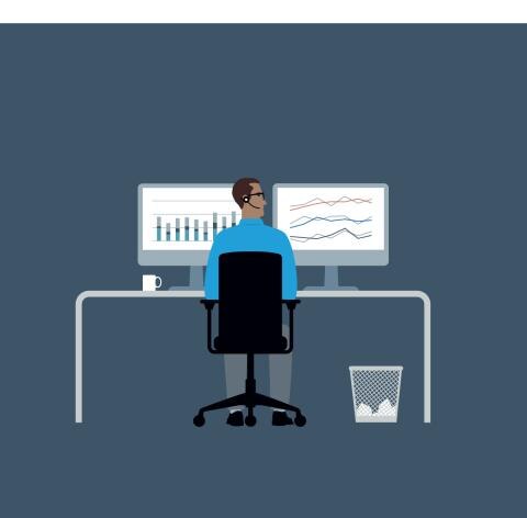 Man sitting at a desk with two computer screens with bar graphs